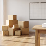 Quel calendrier suivre semaine après semaine avant un déménagement ? Appartement lumineux avec cartons de déménagement, calendrier mural vierge et feuilles de planification disposées sur une table en bois.